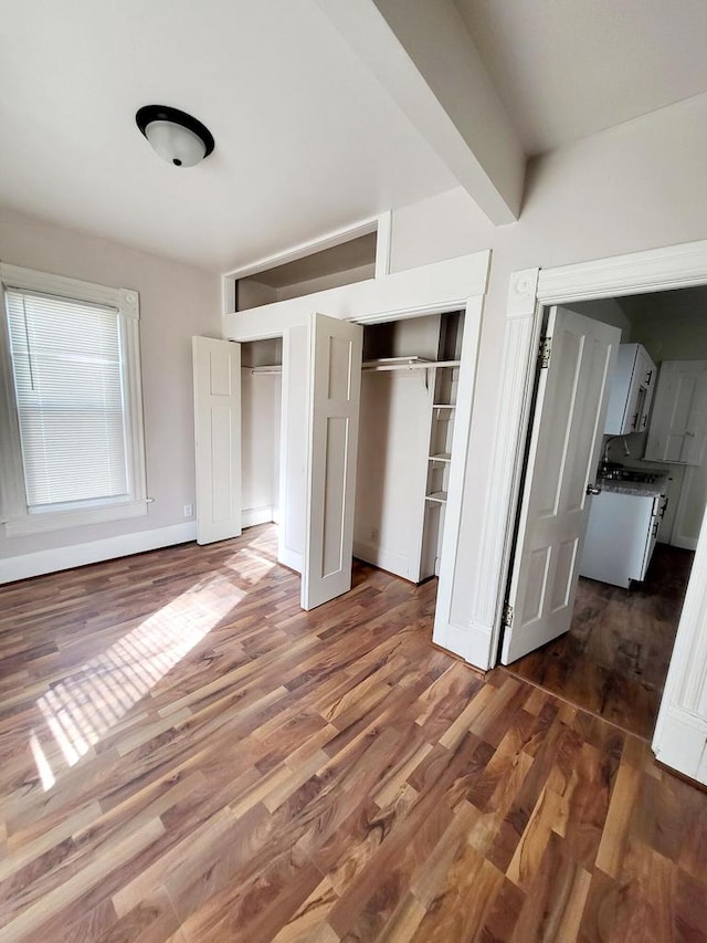 unfurnished bedroom featuring dark hardwood / wood-style floors and beam ceiling