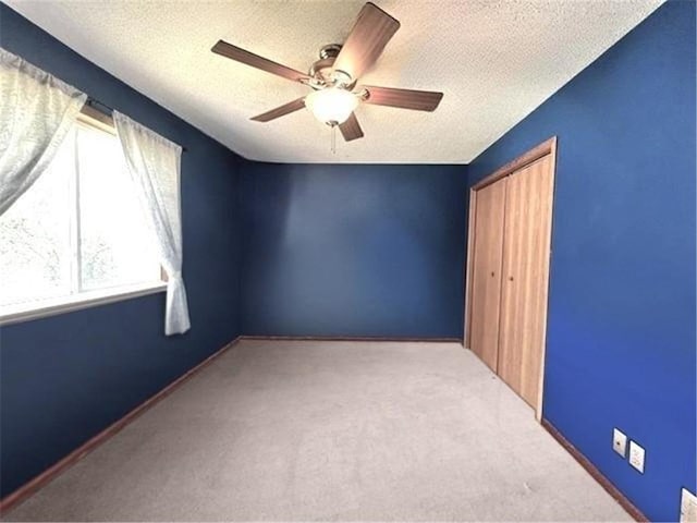 carpeted spare room with a textured ceiling and ceiling fan