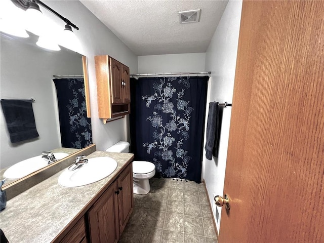 bathroom with vanity, a textured ceiling, toilet, and tile patterned floors