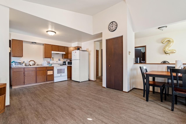 kitchen with a high ceiling, wood-type flooring, and white appliances