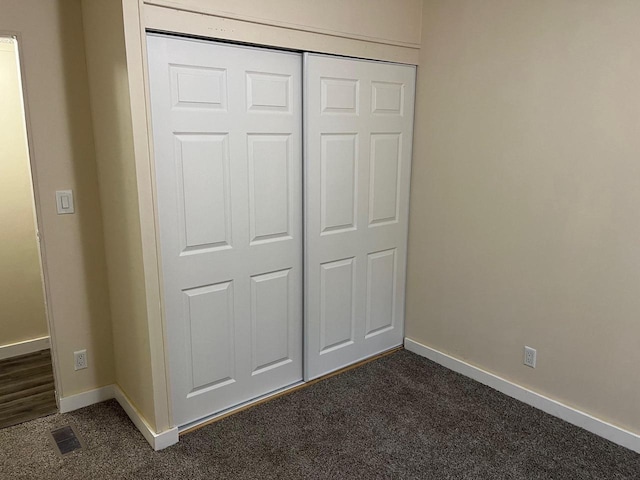 unfurnished bedroom featuring a closet and dark carpet