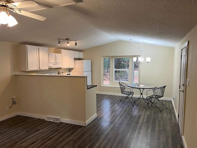 kitchen with lofted ceiling, dark wood-type flooring, kitchen peninsula, white cabinets, and white fridge