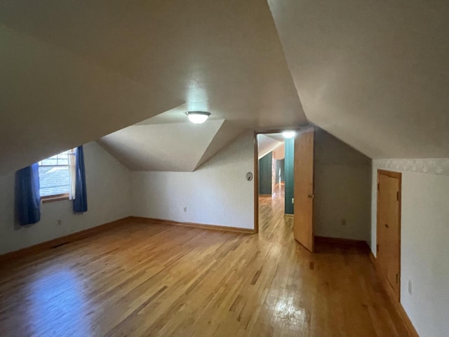 bonus room with lofted ceiling and light wood-type flooring