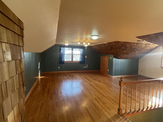 additional living space featuring wood walls, wood-type flooring, and vaulted ceiling