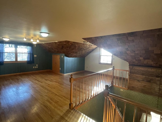 additional living space with hardwood / wood-style flooring, vaulted ceiling, and wood walls