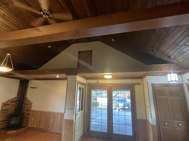 entryway featuring vaulted ceiling with beams, a wood stove, french doors, and light wood-type flooring