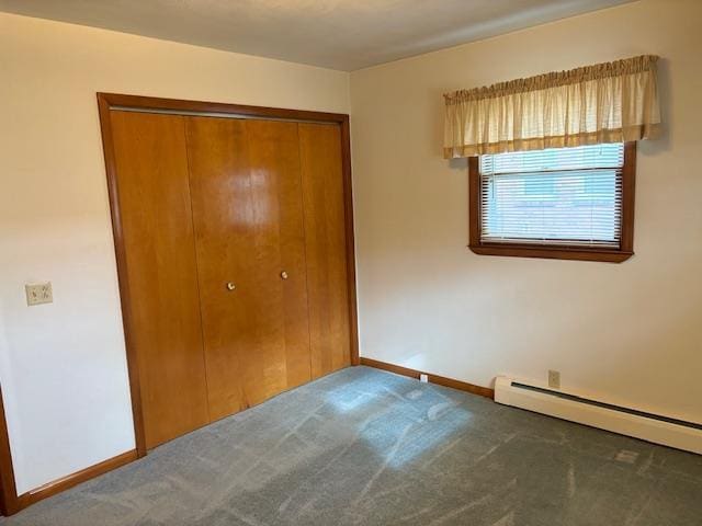 unfurnished bedroom featuring a closet, carpet, and a baseboard heating unit