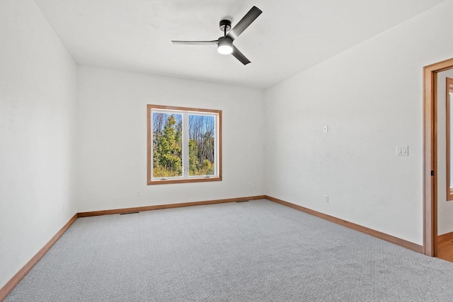 carpeted spare room featuring baseboards, ceiling fan, and visible vents
