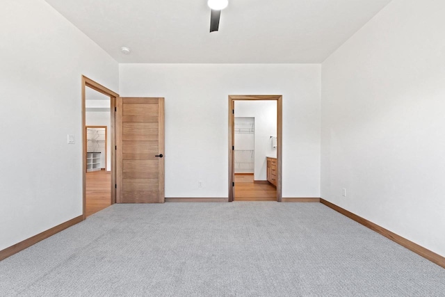 unfurnished bedroom featuring carpet floors, baseboards, ceiling fan, and ensuite bath
