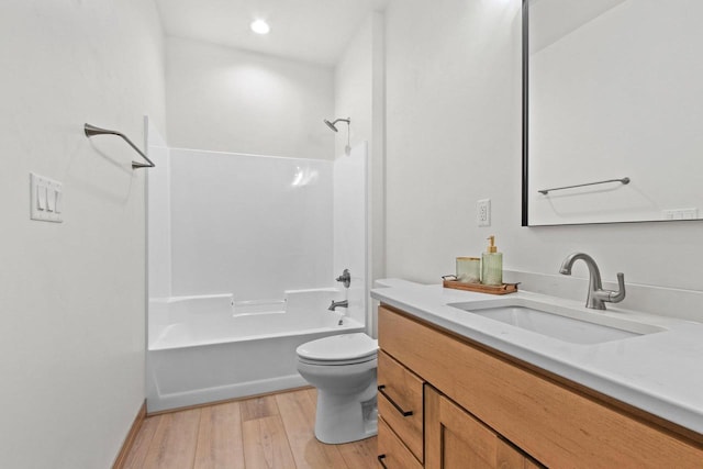 bathroom with vanity, wood finished floors, toilet, baseboards, and bathtub / shower combination