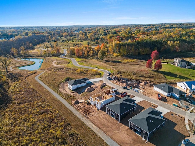 birds eye view of property featuring a water view and a wooded view
