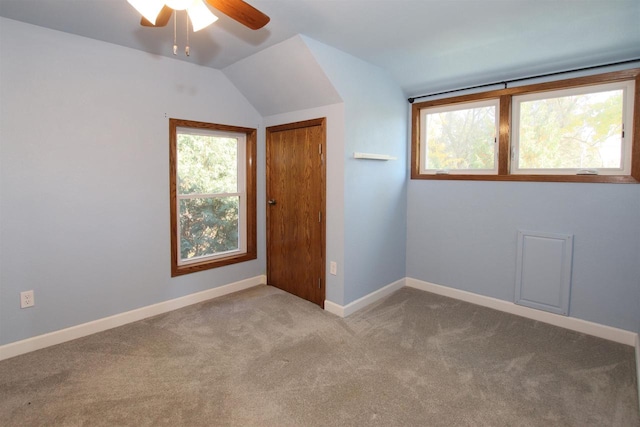 carpeted spare room featuring lofted ceiling, baseboards, and ceiling fan