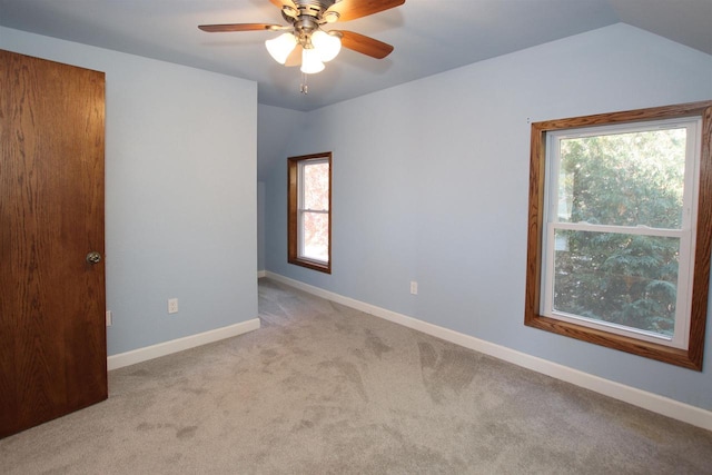 spare room with vaulted ceiling, carpet flooring, baseboards, and ceiling fan