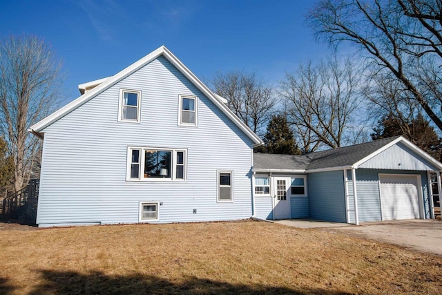 rear view of house with a yard, a garage, and driveway