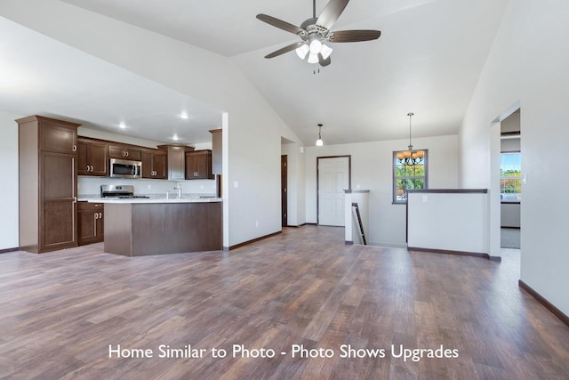 kitchen featuring appliances with stainless steel finishes, hanging light fixtures, dark brown cabinetry, vaulted ceiling, and dark wood-type flooring