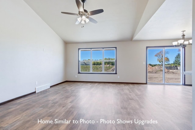 empty room featuring vaulted ceiling, wood-type flooring, and ceiling fan with notable chandelier