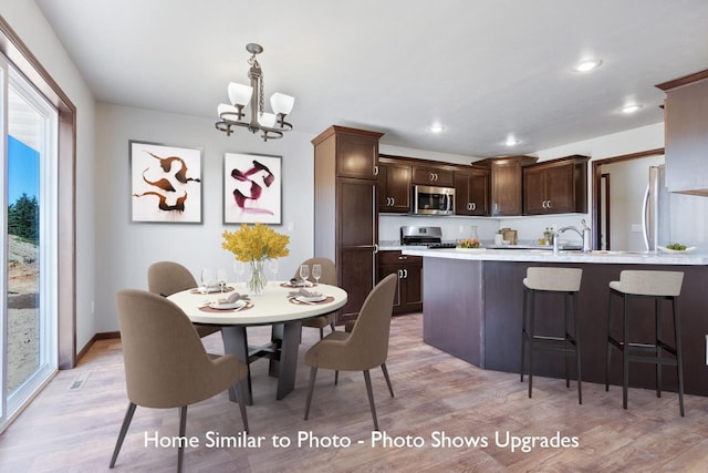 dining space with light hardwood / wood-style flooring, a chandelier, and sink