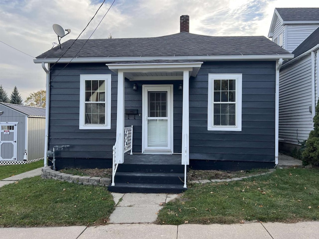 bungalow-style house featuring a storage shed and a front lawn