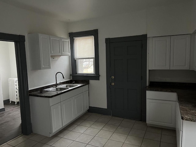 kitchen with sink, radiator heating unit, and white cabinets