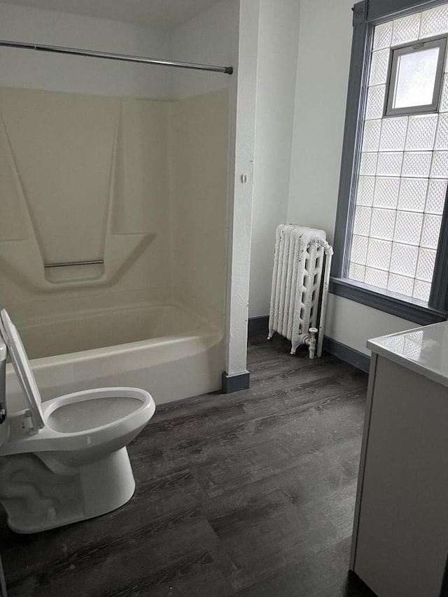 full bathroom with toilet, hardwood / wood-style floors, vanity, washtub / shower combination, and radiator heating unit