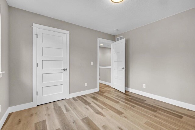 unfurnished bedroom featuring light hardwood / wood-style floors and a textured ceiling