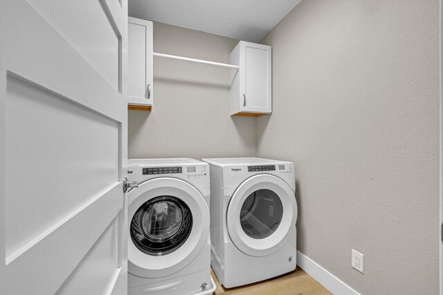 clothes washing area featuring separate washer and dryer and cabinets