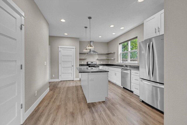 kitchen with stainless steel appliances, pendant lighting, a kitchen island, and white cabinets