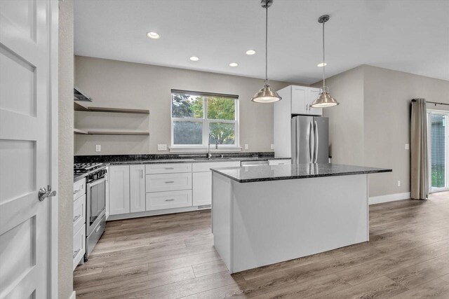 kitchen with a kitchen island, white cabinetry, stainless steel appliances, and light hardwood / wood-style floors