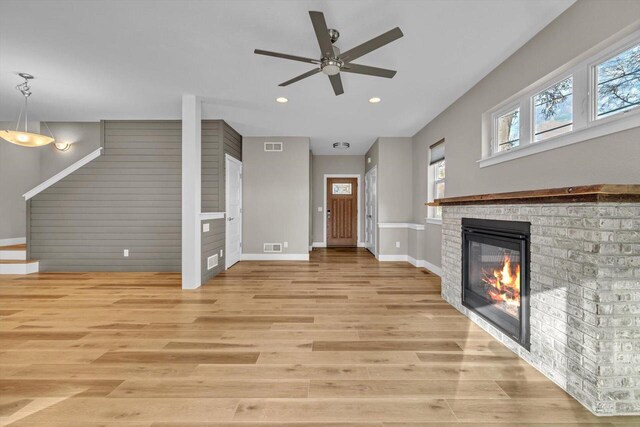 unfurnished living room featuring a fireplace, light hardwood / wood-style floors, and ceiling fan