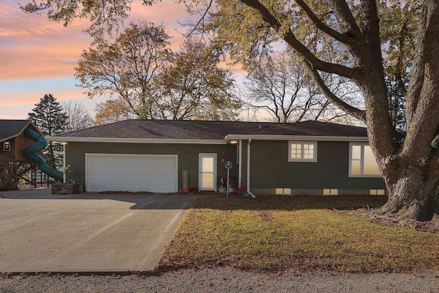 ranch-style house featuring a garage and a lawn