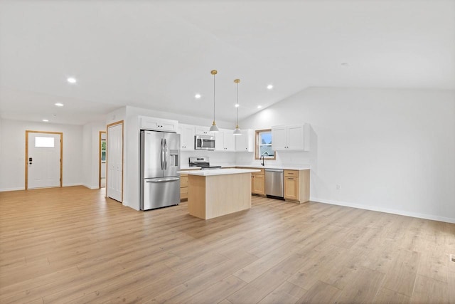 kitchen featuring a center island, vaulted ceiling, pendant lighting, appliances with stainless steel finishes, and light hardwood / wood-style floors