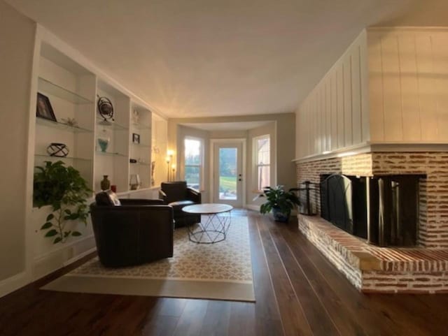 living room featuring a brick fireplace and dark hardwood / wood-style floors