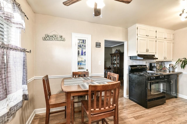 kitchen featuring light hardwood / wood-style flooring, tasteful backsplash, black range with gas cooktop, and ceiling fan