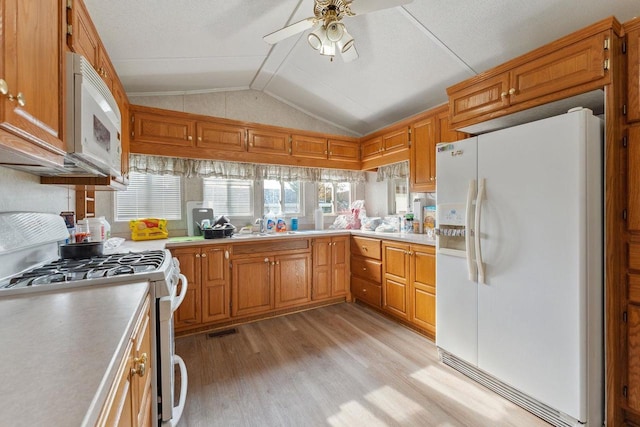 kitchen featuring lofted ceiling, sink, light wood-type flooring, white appliances, and ceiling fan