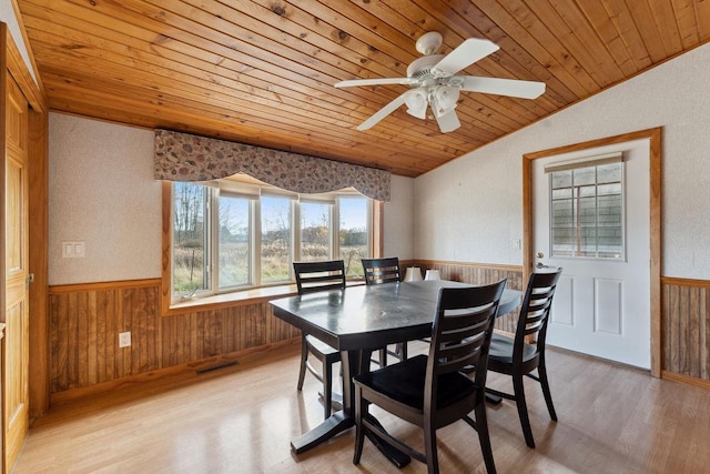 dining room featuring wood ceiling, light hardwood / wood-style flooring, vaulted ceiling, ceiling fan, and wood walls