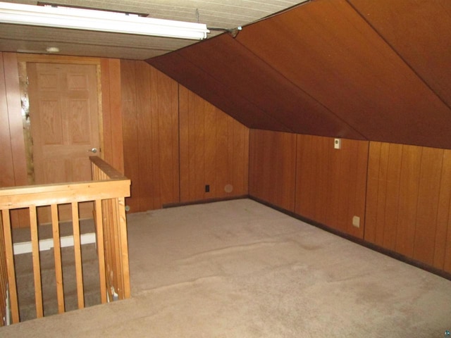 additional living space featuring light carpet, lofted ceiling, and wood walls