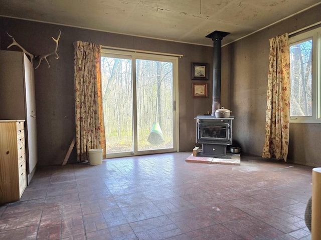 unfurnished living room with a wood stove and a wealth of natural light