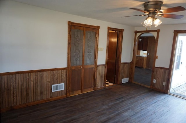 unfurnished room featuring ceiling fan, wood walls, and dark hardwood / wood-style floors