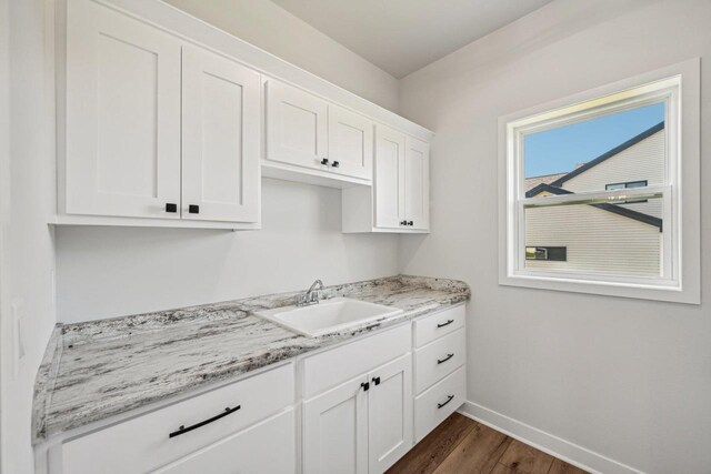 kitchen with light stone countertops, sink, white cabinetry, and dark hardwood / wood-style flooring