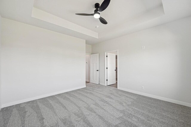 carpeted empty room with ceiling fan and a raised ceiling