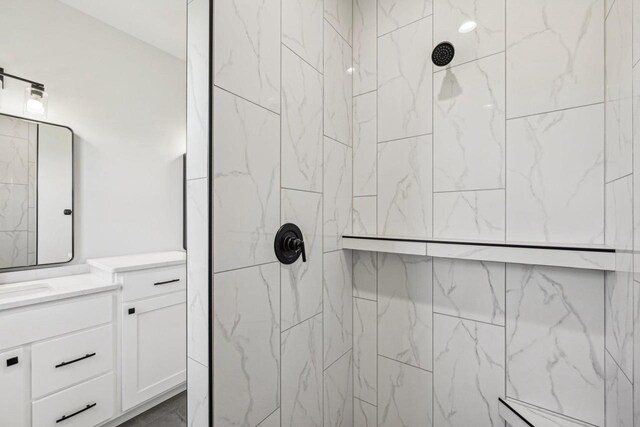 bathroom with a tile shower and vanity