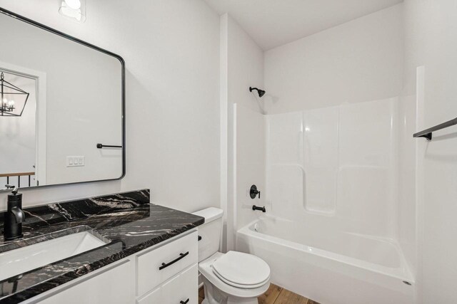 full bathroom featuring shower / bathing tub combination, hardwood / wood-style floors, toilet, vanity, and a chandelier