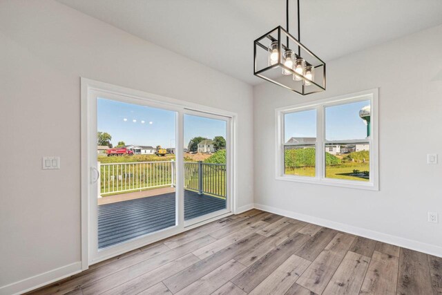 unfurnished dining area with light hardwood / wood-style flooring, a wealth of natural light, and an inviting chandelier