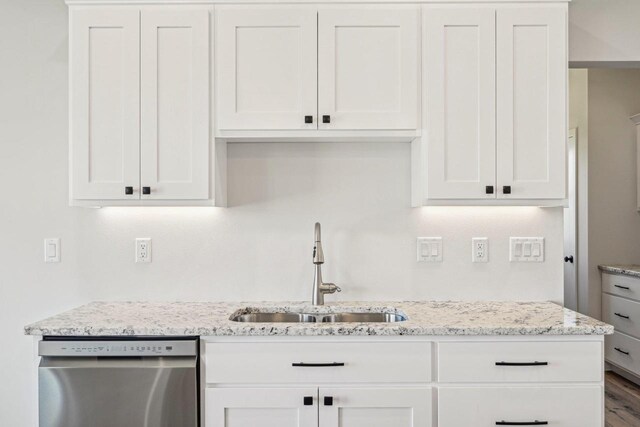 kitchen with white cabinets, light stone countertops, stainless steel dishwasher, and sink