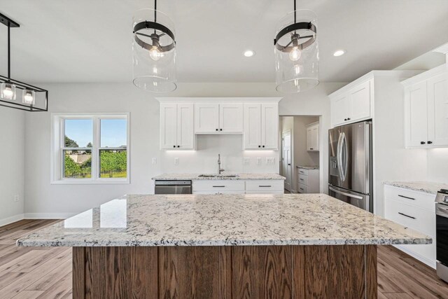 kitchen with light hardwood / wood-style floors, stainless steel appliances, sink, and a kitchen island