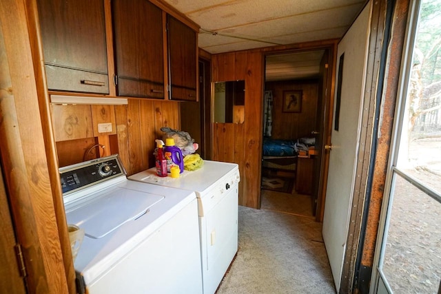 clothes washing area featuring cabinets, light colored carpet, washing machine and dryer, and wooden walls