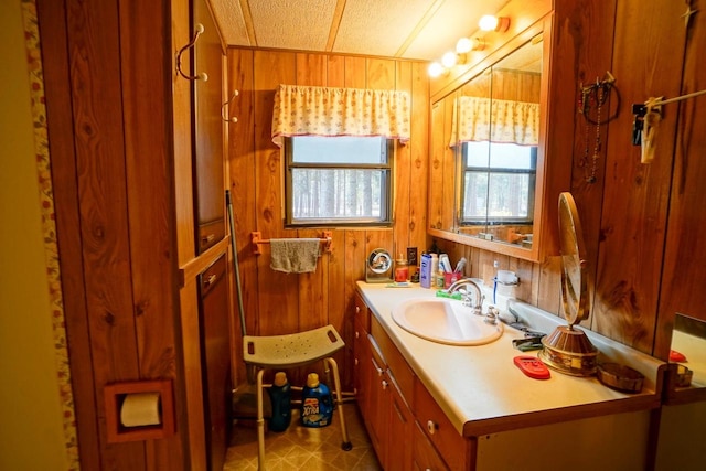 bathroom with vanity, wood walls, and a textured ceiling