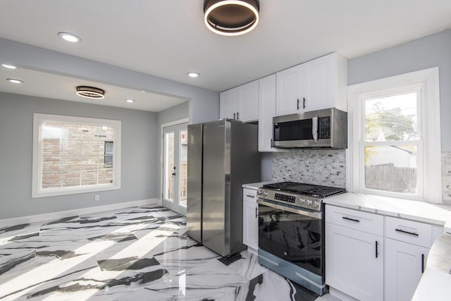 kitchen featuring white cabinetry, stainless steel appliances, light stone countertops, and tasteful backsplash