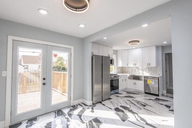 kitchen with french doors, stainless steel appliances, backsplash, sink, and white cabinetry