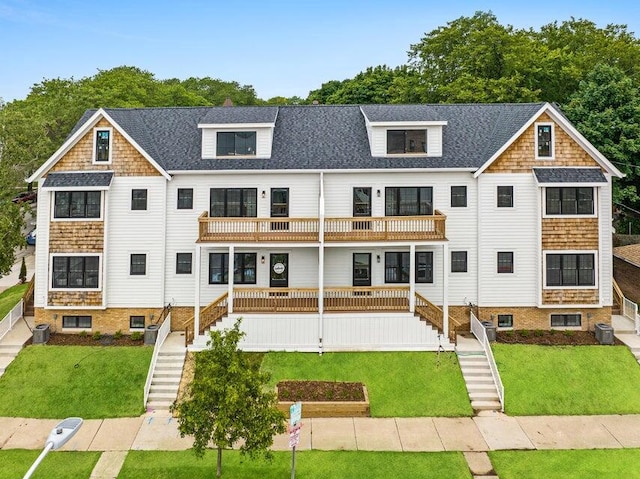 rear view of property featuring a lawn, a balcony, and central AC unit